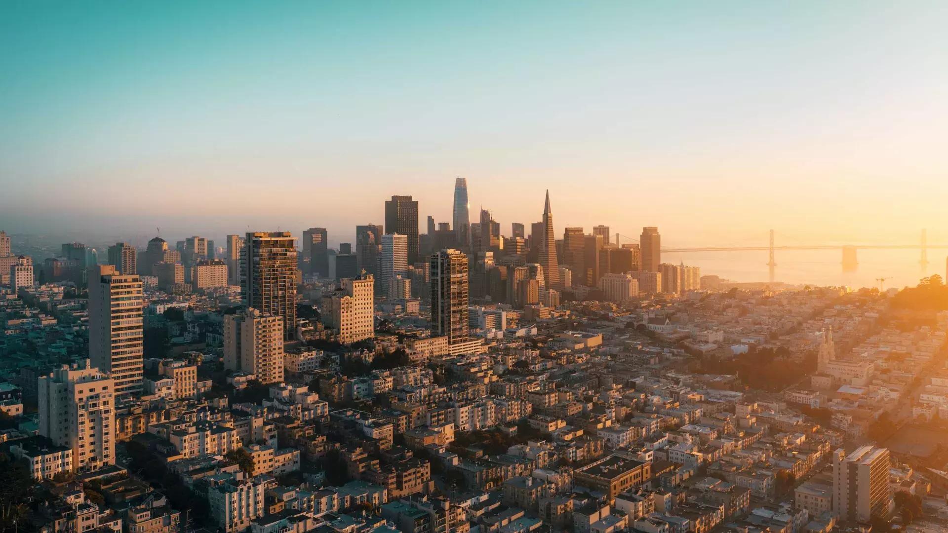 The skyline of San Francisco is seen from the air in a golden light.
